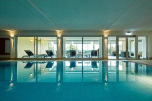 a swimming pool with chairs and tables in a building at NaturKulturHotel Stumpf in Neunkirchen