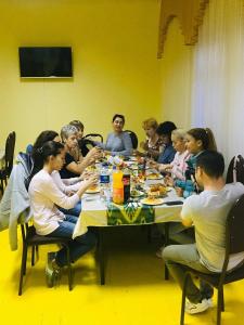 un grupo de personas sentadas alrededor de una mesa comiendo en BUKHARA HOUSE hotel, en Bukhara
