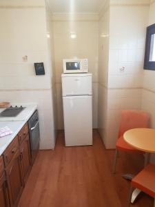 una pequeña cocina con nevera blanca y microondas en Apartamentos Parot Quality, en Santa Eulària des Riu