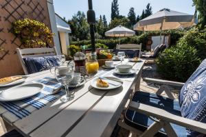 Villa Oleander في Áfra: طاولة خشبية مع لوحات من الطعام وكؤوس النبيذ