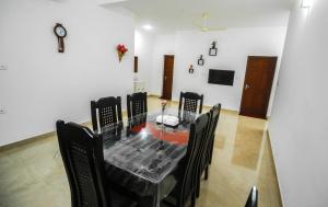 a dining room with a table and black chairs at Snehatheeram Homestay in Alleppey
