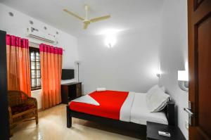 a bedroom with a red and white bed and a window at Snehatheeram Homestay in Alleppey