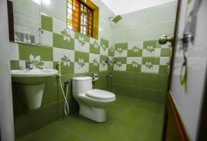 a green and white bathroom with a toilet and sink at Snehatheeram Homestay in Alleppey +8 photos