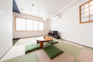 Una habitación con una mesa y cojines verdes en el suelo. en Yado Hachiemon, en Osaka