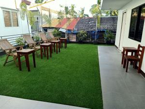 patio ze stołami i krzesłami oraz zieloną trawą w obiekcie Magarbo Hotel w mieście Boracay