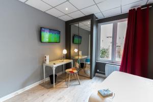 Schlafzimmer mit einem Bett, einem Schreibtisch und einem TV in der Unterkunft Chenal Hotel in Beauvais