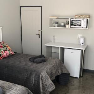 a bedroom with a bed and a table and a desk at The Red Chimney in Pretoria +7 photos