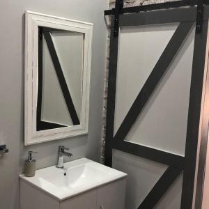 een badkamer met een witte wastafel en een spiegel bij The Red Chimney in Pretoria