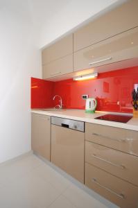 a kitchen with red walls and white cabinets and a sink at Apartment Antea in Split