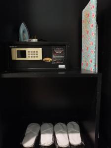 a black shelf with a microwave and a row of shoes at Kimberley Hotel Georgetown in George Town