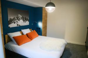 a blue bedroom with a bed with two orange pillows at Appart'Hotel Aiguille Verte & Spa in Chamonix-Mont-Blanc