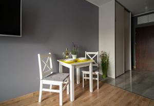 ウッチにあるApartamentylove - Apartament Więckowski, prywatny garaż podziemny opcjonalnieの白いダイニングテーブル(椅子2脚、テーブル付)