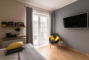 1 dormitorio con 1 cama, 1 silla y TV en Apartamentylove - Apartament Więckowski, en Łódź