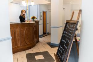 a woman is standing at a counter in a restaurant at Chenal Hotel in Beauvais