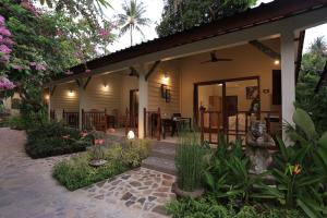 a house with a porch with a bench and flowers at Puri Mas Boutique Resort & Spa in Senggigi