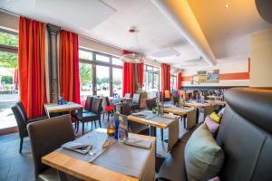 Hotel Cochemer Jung في كوشيم: مطعم بالطاولات والكراسي والستائر الحمراء