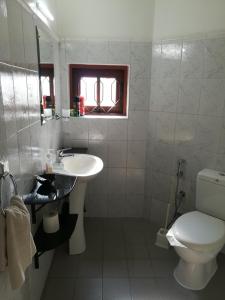 La salle de bains blanche est pourvue de toilettes et d'un lavabo. dans l'établissement Ayubowan Guesthouse, à Negombo