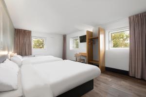 een hotelkamer met 2 bedden en 2 ramen bij B&B HOTEL Lyon Centre Monplaisir in Lyon
