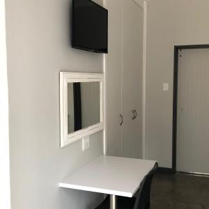 a white table with a mirror and a tv on a wall at The Red Chimney in Pretoria