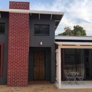 a brick house with a door and a table at The Red Chimney in Pretoria