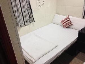 a small white couch with a pillow sitting on it at Shanghai Hostel HK in Hong Kong