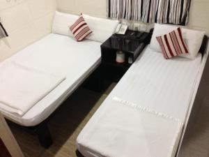 two beds in a room with white sheets and pillows at Shanghai Hostel HK in Hong Kong