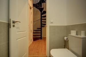 a bathroom with a toilet and a spiral staircase at Apartamentos Setas Center in Seville