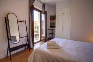 a bedroom with a white bed and a mirror at Apartamentos Setas Center in Seville