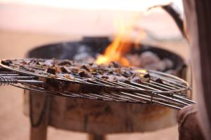 a person holding a tray of food on a grill at Tarmguist in Tighmert
