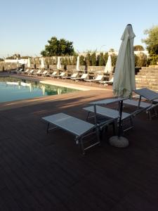 een tafel met stoelen en een parasol naast een zwembad bij B&B nna'vigna in Viagrande