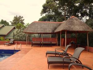 een patio met stoelen, een grote parasol en een zwembad bij Governors Club in Entebbe