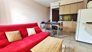 a living room with a red couch and a kitchen at Agroktima Fourki in Aigio