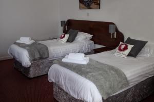 two beds in a hotel room with towels on them at Oliver Twist Country Inn in Wisbech