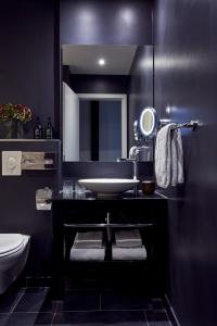 a black bathroom with a sink and a mirror at Park Centraal Amsterdam in Amsterdam