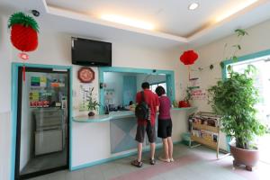 dos personas de pie en un mostrador en una cocina en Fairway Hotel en Melaka