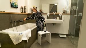 eine Frau, die neben einer Badewanne im Bad steht in der Unterkunft FIRST im FIRST Sellin, Penthouse Paradies am Meer in Ostseebad Sellin