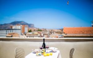 a white table with wine glasses and a view of a city at Albergo Athenaeum in Palermo