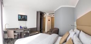 a bedroom with a bed and a desk and a table at Hotel Santo in Karlsruhe