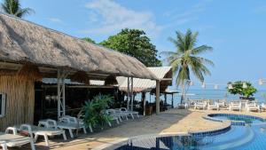 a resort with a pool and chairs and the ocean at Lanta New Coconut Bungalow in Ko Lanta