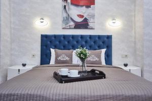a bed with a blue head board with two cups and flowers at Panoramic Plaza Apartments in Odesa +86 photos