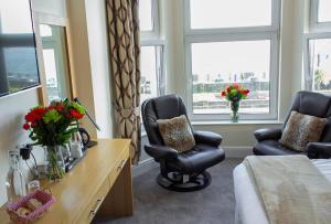 a hotel room with a bed and two chairs and windows at Ellan Vannin Hotel in Douglas