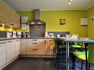 uma cozinha com armários de madeira e paredes verdes em Alluring Holiday Home in Waimes with Garden em Waimes