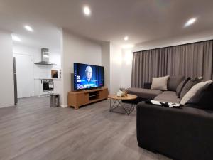 uma sala de estar com um sofá e uma televisão de ecrã plano em Hello Seaview! 4 BRs House in Central Location! em Oamaru