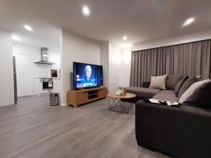 a living room with a couch and a flat screen tv at Hello Seaview! 4 BRs House in Central Location! in Oamaru