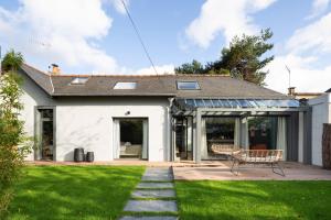 een wit huis met een bank in een tuin bij Maison Castellio by Cocoonr in Rennes