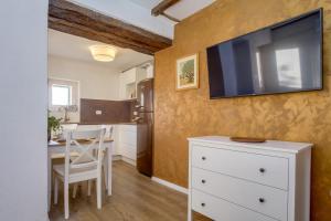 a kitchen with a table and a tv on a wall at Casa Rustica in Mali Lošinj