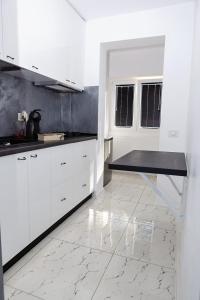 cocina con armarios blancos y suelo de mármol en Archi's Apartament, en Galaţi
