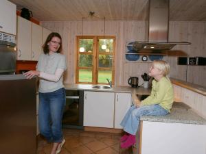 two women standing in a kitchen with a woman sitting on the counter at 8 person holiday home in R dby in Kramnitse