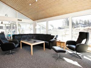 ブロックフスにある12 person holiday home in Blokhusのリビングルーム(黒い革張りのソファ、椅子付)