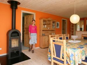 a woman standing in a room with a wood stove at 8 person holiday home in R dby in Kramnitse